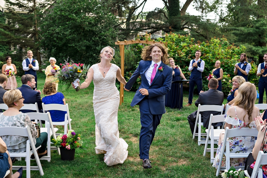 A bride and groom skip down the isle after getting married at the carriage house at rockwood park.